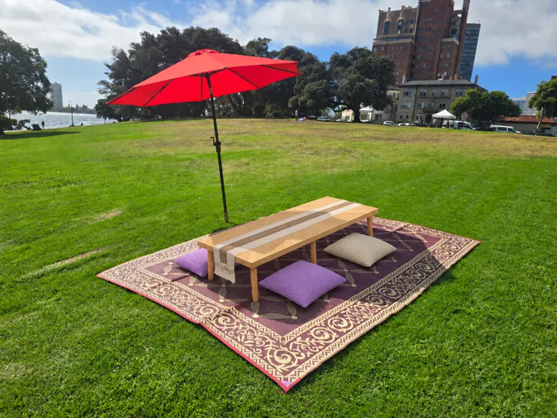 Staged picnic table and cushions beneath a red umbrella